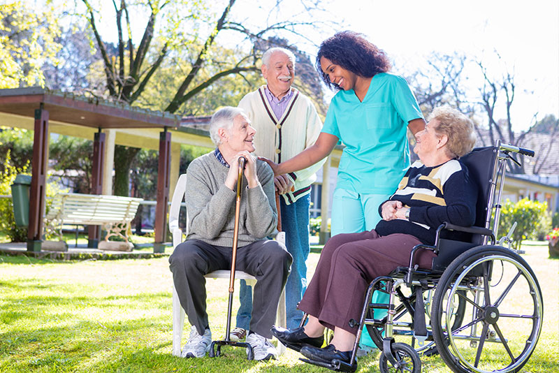 Pflegeszene Aussen mit einer Pflegerin und 3 Rentnern